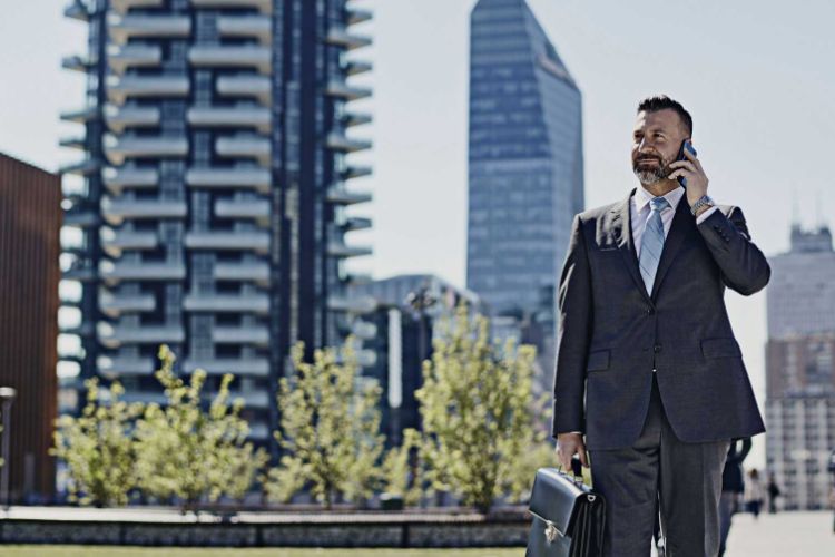 man in a suit walking through a city on a mobile phone