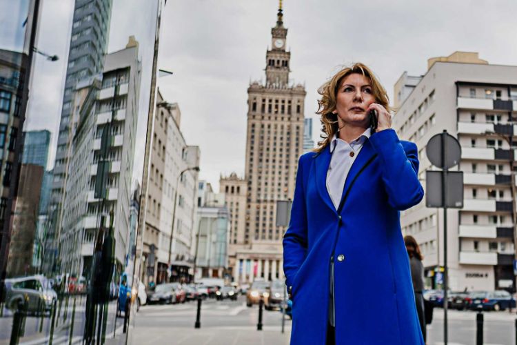 woman in a blue coat in a city centre on the phone