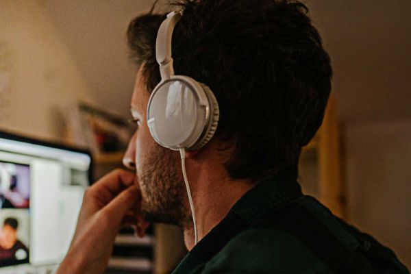 man with headphones on looking at a computer screen at home