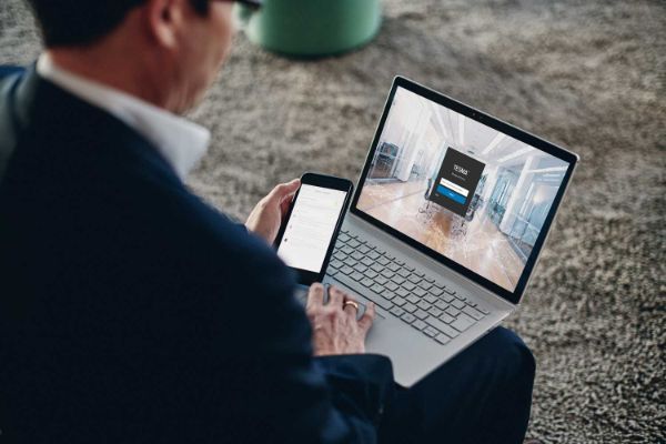 man in a suit looking at a smartphone and a laptop